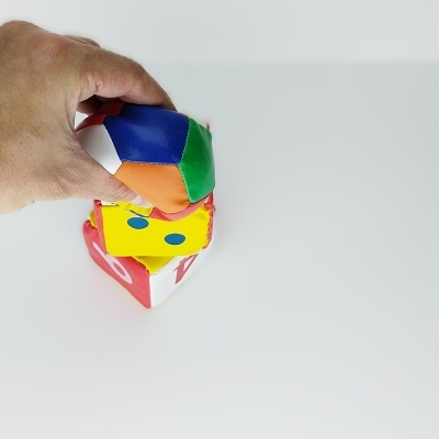 Brinquedo de espuma com blocos e bola coloridos sendo segurado por uma mão