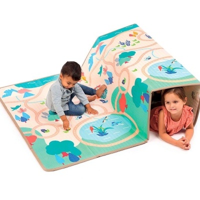 Tapete infantil colorido com padrão de caminhos, árvores e lago, formando tenda com crianças a brincar