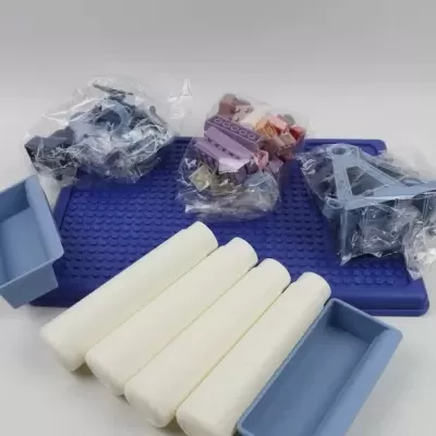 Conjunto de acessórios para modelagem ou pintura com base azul, rolos de espuma brancos e recipientes azuis.