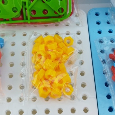 Peças de encaixe coloridas em sacos transparentes sobre placas de base perfuradas