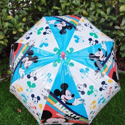 Guarda-chuva colorido com padrão do Mickey Mouse sobre relva artificial e folhagem