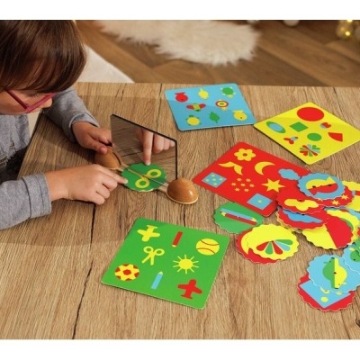 Jogo educativo com cartas coloridas e espelho, criança a brincar numa mesa de madeira