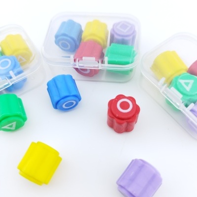 Peças de plástico coloridas com padrões geométricos e símbolos em caixas transparentes