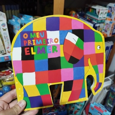 Livro infantil colorido em forma de elefante com texto O MEU PRIMEIRO ELMER