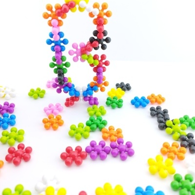 Peças de plástico coloridas em forma de flores encaixadas com várias cores numa superfície branca.