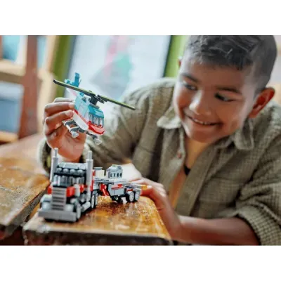 Criança a brincar com brinquedos helicóptero e camião de construção de plástico em mesa