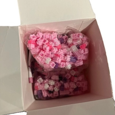 Caixa branca com sacos plásticos cheios de pequenos objetos plásticos coloridos