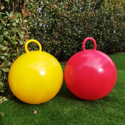 Balões grandes amarelo e vermelho com alças na relva junto a arbustos
