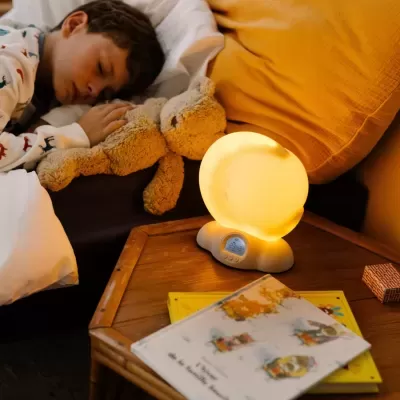 Lâmpada amarela quente em mesa de cabeceira com criança a dormir