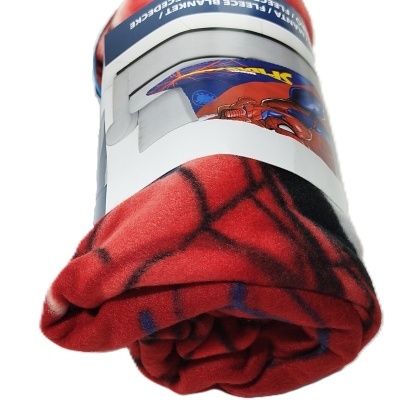 Manta vermelha enrolada com padrão do Homem-Aranha e embalagem branca com texto.
