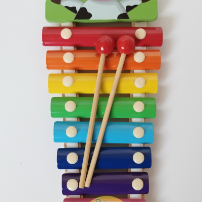 Xilofone colorido de madeira com decoração de vaca e baquetas vermelhas
