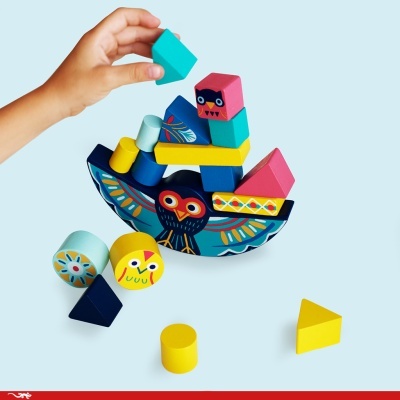 Blocos de madeira coloridos com padrões de coruja sendo empilhados por uma mão de criança