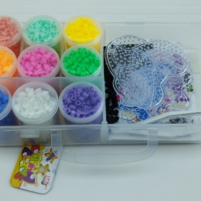 Estojo transparente com frascos coloridos de pérolas pequenas e placas de moldar.