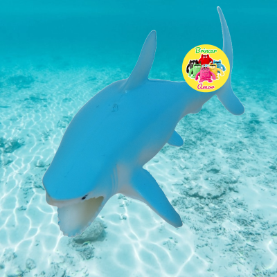 Figura de tubarão azul no fundo do mar com selo amarelo Brincar Amor