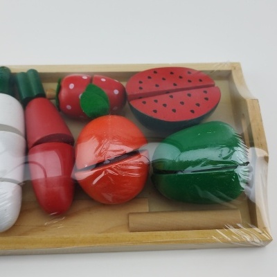 Brinquedo de madeira de legumes e frutas coloridos numa bandeja embalados em plástico transparente