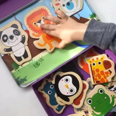 Puzzles de madeira coloridos com desenhos de animais e uma mão infantil a tocar numa peça