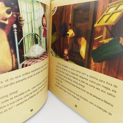 Livro infantil aberto com história e desenhos dos personagens Urso e menina em ambiente caseiro.