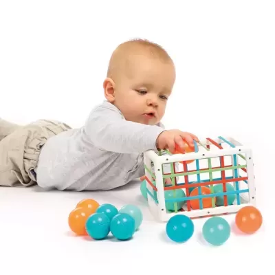 Criança a brincar com brinquedo colorido de bolas e caixa de plástico