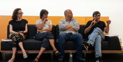 quatro pessoas sentadas num sofá preto com estrutura de madeira