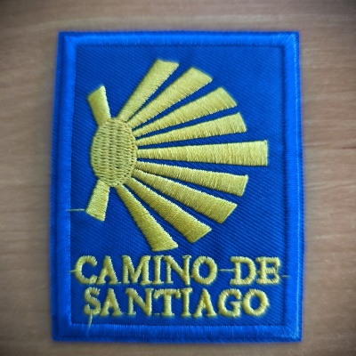 Emblema bordado azul e amarelo com texto Camino de Santiago