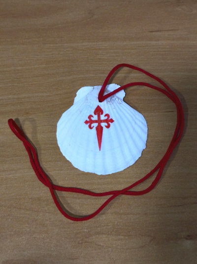 Concha branca com símbolo vermelho e cordão vermelho sobre madeira clara