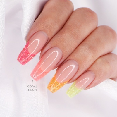 Unhas postiças com pontas neon e glitter em dedos femininos sobre tecido branco.
