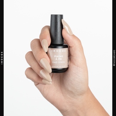 Mão com unhas compridas pintadas a nude a segurar verniz gel Inocos Piadas à Pai