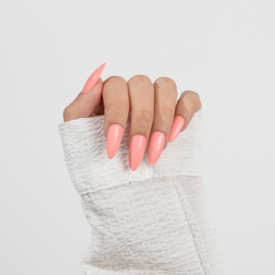 Unhas stiletto cor de rosa claro numa mão segurando tecido branco