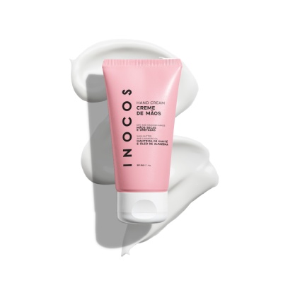 Tubo cor-de-rosa de creme de mãos INOCOS com tampa branca sobre textura cremosa
