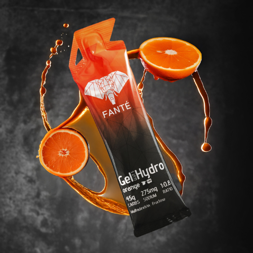 FANTÉ GEL HYDRO 45 LARANJA Embalagem individual laranja e preta de gel energético FANTÉ com fatias de laranja e gotas de suco em fundo escuro.