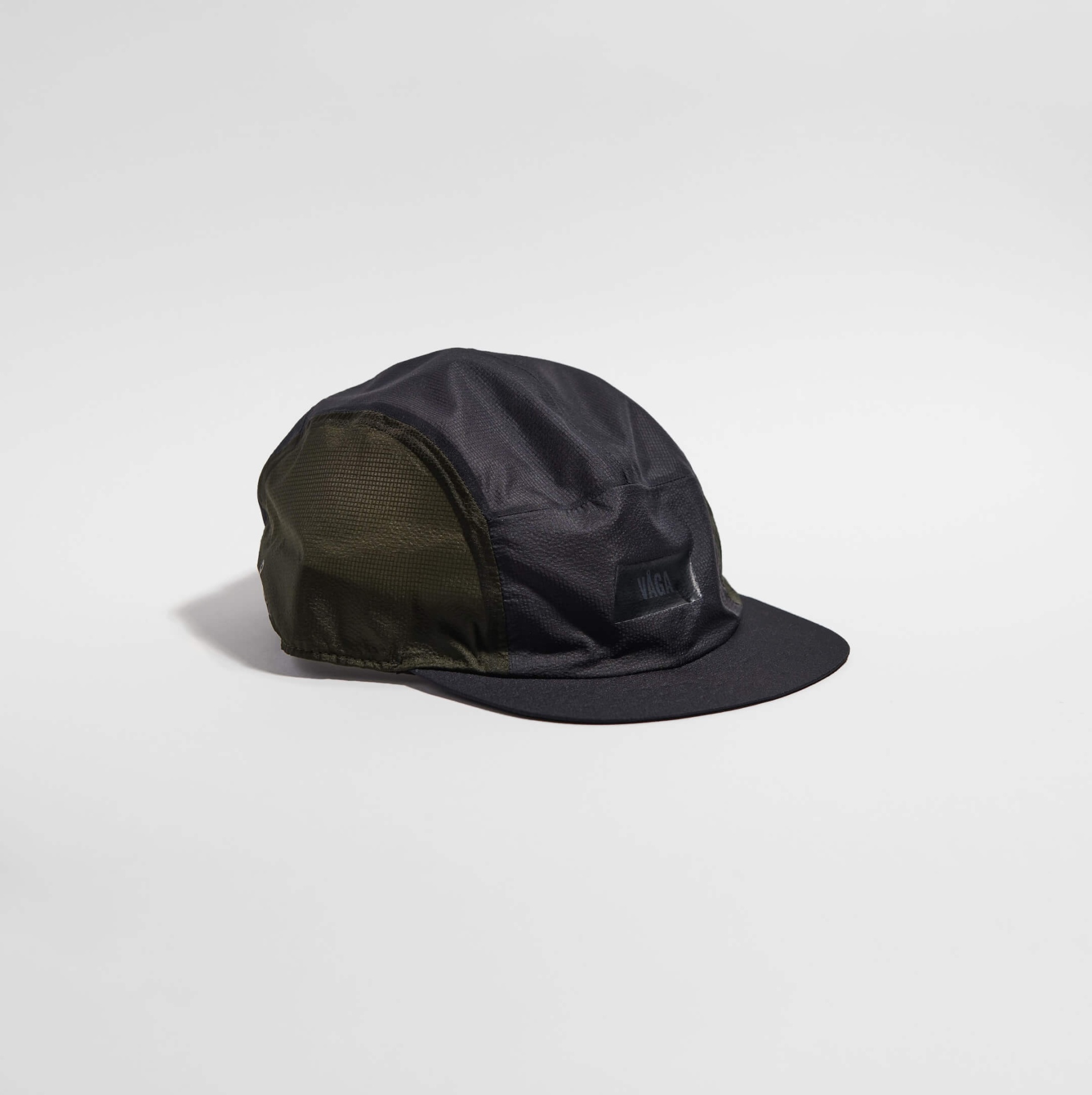 VÅGA FEATHER LIGHT CAP - CHARCOAL Boné desportivo preto e verde-oliva com etiqueta VÅGA sobre fundo branco
