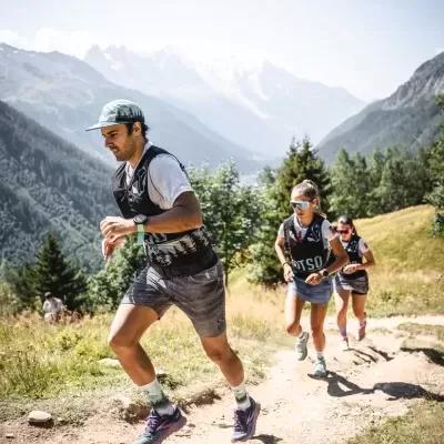 Três corredores em trilho montanhoso com roupa e ténis desportivos