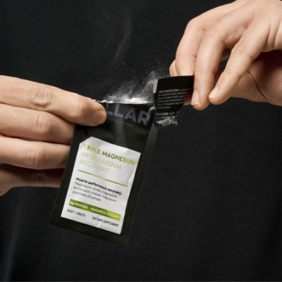 Embalagem preta e branca de suplemento com pó branco saindo, mãos a abrir