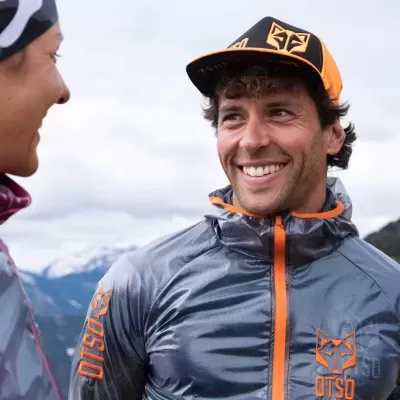 Homem com casaco cinzento e detalhes laranja OTSO ao ar livre