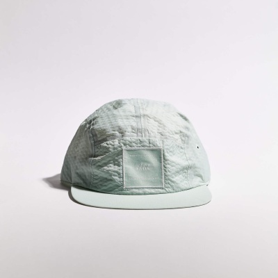 Boné verde-água claro com etiqueta frontal e aba curva em fundo branco
