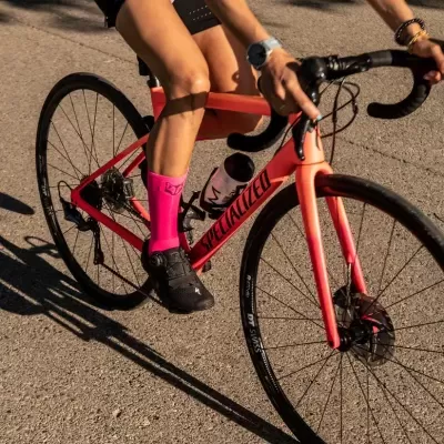 Bicicleta de estrada rosa com ciclista usando meias rosa e sapatos pretos