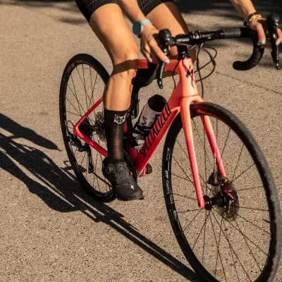 Bicicleta de estrada rosa Specialized com ciclista em asfalto