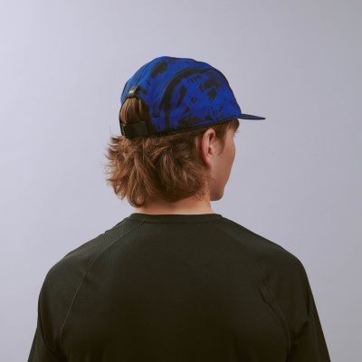 Boné azul e preto com padrão abstracto visto de trás, em pessoa com cabelo castanho e camisa preta.