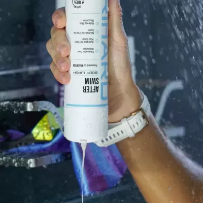 Frasco branco a dispensar líquido branco espesso para mão sob água em queda.