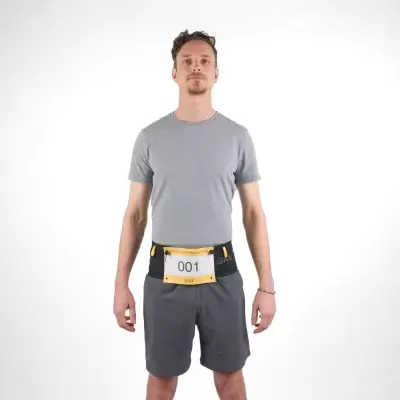 Homem com t-shirt cinzenta clara, calções cinzentos escuros e saco/cinto desportivo preto com número 001