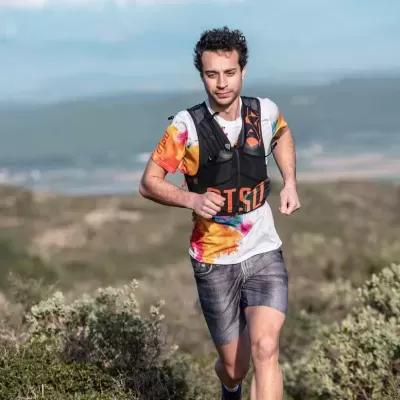 Homem a correr em trilho com camiseta colorida e colete preto