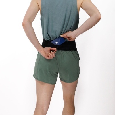 Pessoa de costas com roupa desportiva e cinto preto a guardar objeto azul