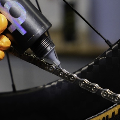 Aplicação de lubrificante em corrente de bicicleta com pneu Continental preto e superfície de carbono