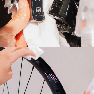 Limpeza de peças de bicicleta com pano branco, incluindo trocador com código QR e aro da roda preto.