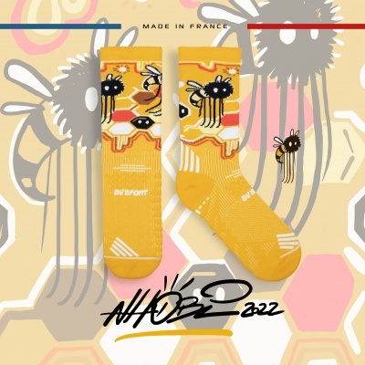 Meias amarelas com padrão de abelhas e texto 'IN SPORT' em fundo colorido com hexágonos e abelhas.