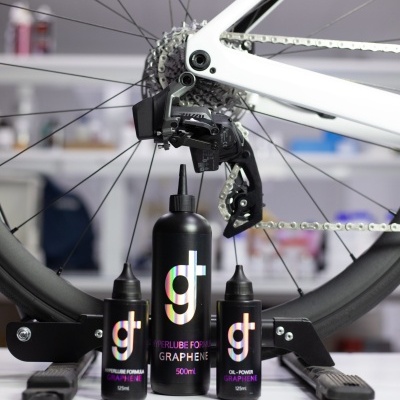 Roda traseira de bicicleta branca com três frascos de lubrificante para bicicleta gt graphene numa bancada branca