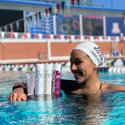 Homem na piscina com touca branca e três latas de bebida energética