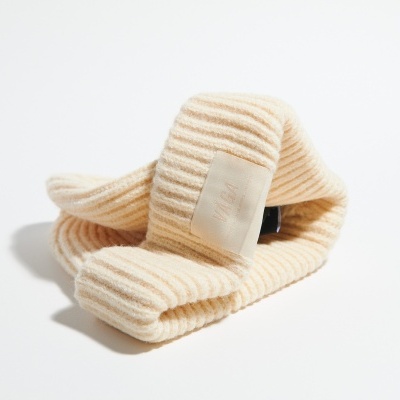 Cachecol ribeado bege claro dobrado sobre fundo branco