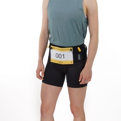 Pessoa com roupa desportiva e faixa amarela na cintura com número de identificação 001 em fundo branco