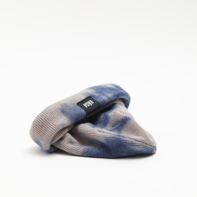 Gorro de malha bege e azul com etiqueta 'NOW' num fundo branco